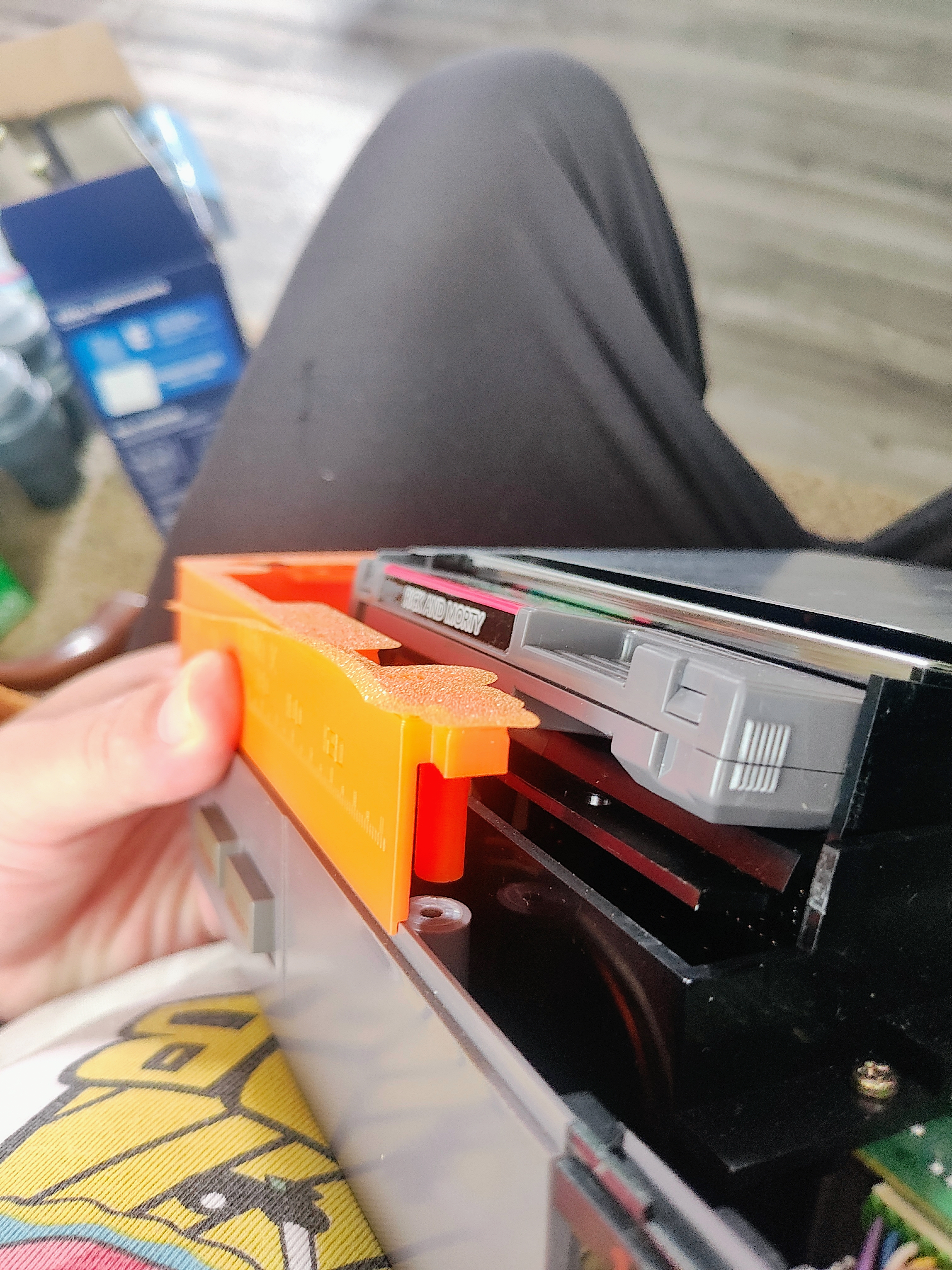 September 6, 2026 · Physical fitting in progress. Orange printed part beside the cartridge inside the open NES.