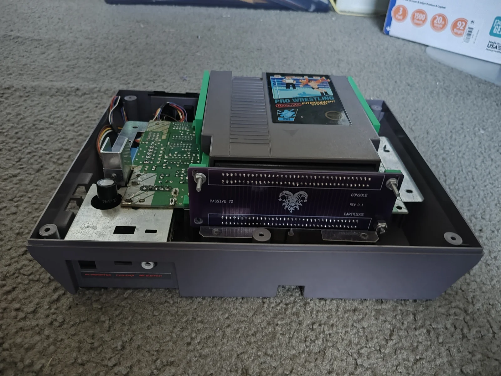 Purple Jester connector board and green printed tray assembled in an open NES, with a Pro Wrestling cartridge seated in the tray